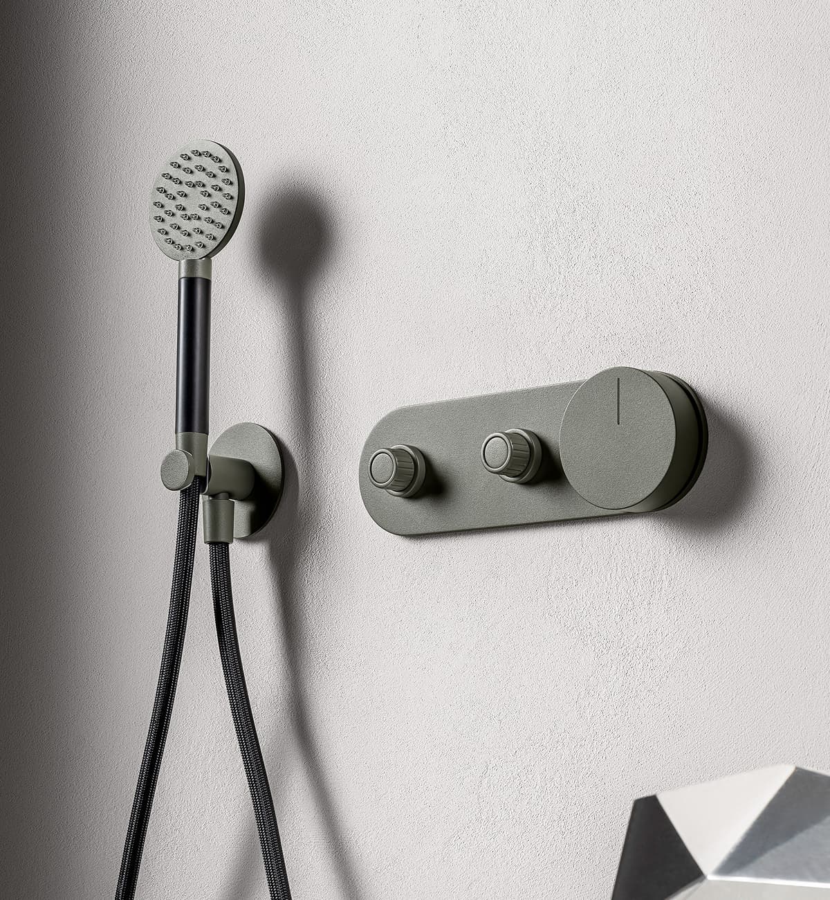 L'immagine mostra il doccino con manopole cilindriche di un sistema doccia color verde militare.